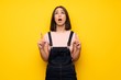 © luismolinero - Young woman over yellow wall surprised and pointing up
