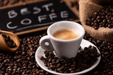 Fototapeta Boho - Expresso coffee cup close-up over dark roasted coffee beans