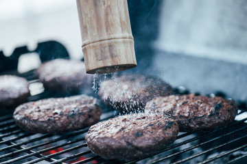 Canvas Print - selective focus of salt falling from salt mill on tasty grilled bbq burger cutlets