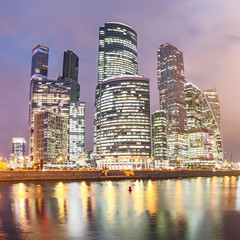 Illuminated Skyscrapers in Moscow City or international business centre at night time with lights, view from water pond embankment with reflections