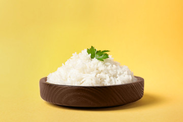 Bowl of boiled rice on color background