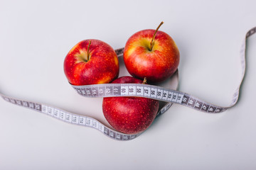 Red apple wrapped centimeter lies on a white table. Apple diet