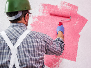 Professional house painter at work painting the wall