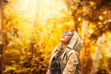 Happy woman throwing leaves. Season and beautiful happy young woman having fun with leaves in autumn park