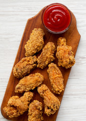 Wall Mural - Chicken wings on rustic wooden board with red pepper sauce over white wooden surface, top view. Flat lay, overhead, from above.