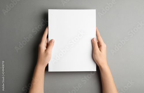 Fotomural Woman holding brochure with blank cover on grey background, top view