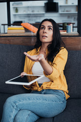 Wall Mural - Surprised beautiful woman in yellow shirt holding digital tablet and looking at water leak