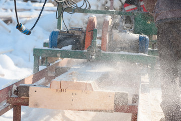 Wall Mural - Sawing boards on the sawmill. Cook lumber in winter. Work on the sawmill.