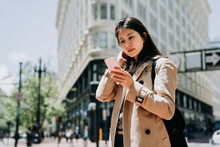 Young Beautiful Asian Woman Tourist With Mobile Phone Reading Online Guide Book Of City Urban San Francisco Information. Girl Traveler Holding Cellphone Looking Online Map Standing On Street.