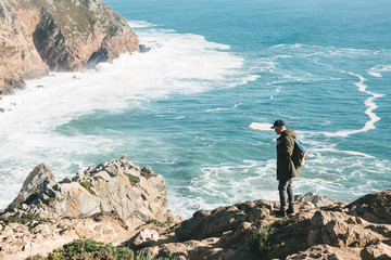 Wall Mural - A man tourist with a backpack stands in solitude at Cape Roca in Portugal.