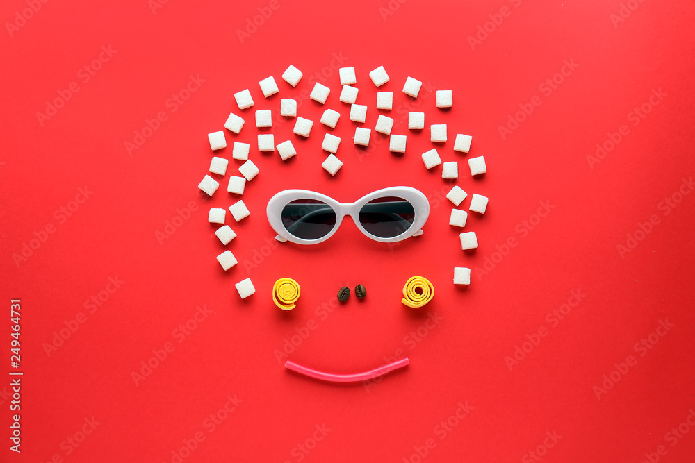 Creative composition with monkey face made of sweets and sunglasses on color background