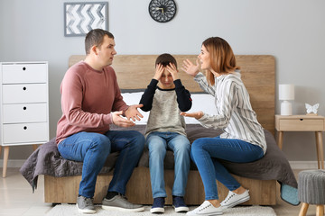 Poster - Sad little boy covering ears while his parents arguing at home