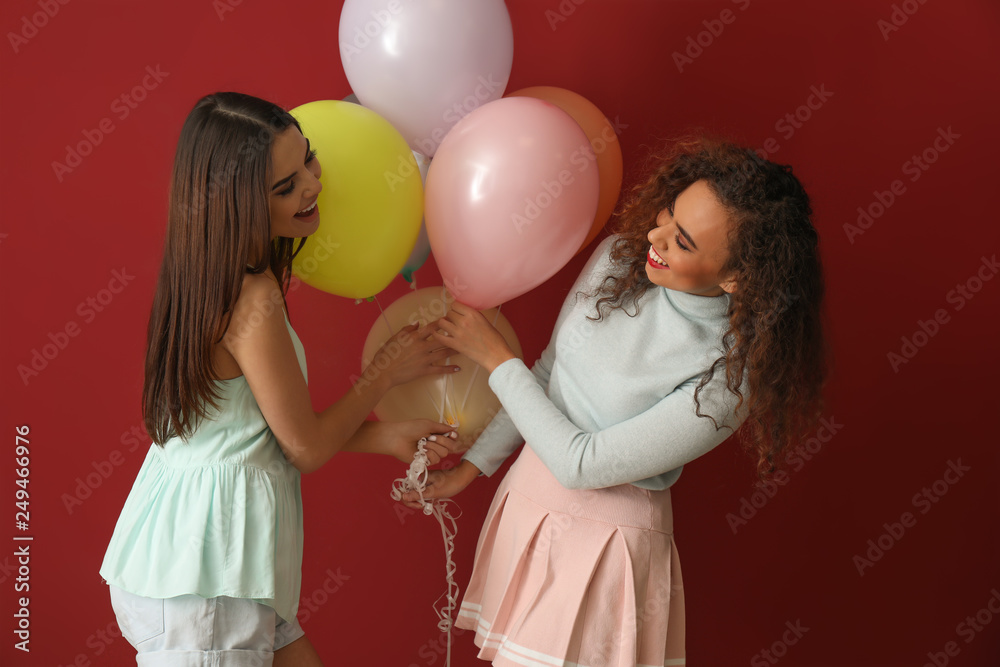 Beautiful young women with balloons on color background