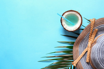 Composition with beach hat, coconut cocktail and tropical leaf on color background