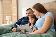 © Pixel-Shot - Happy family reading book in bed