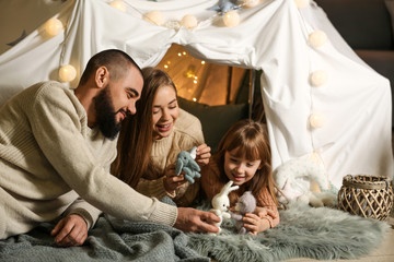 Happy parents playing with their little daughter at home