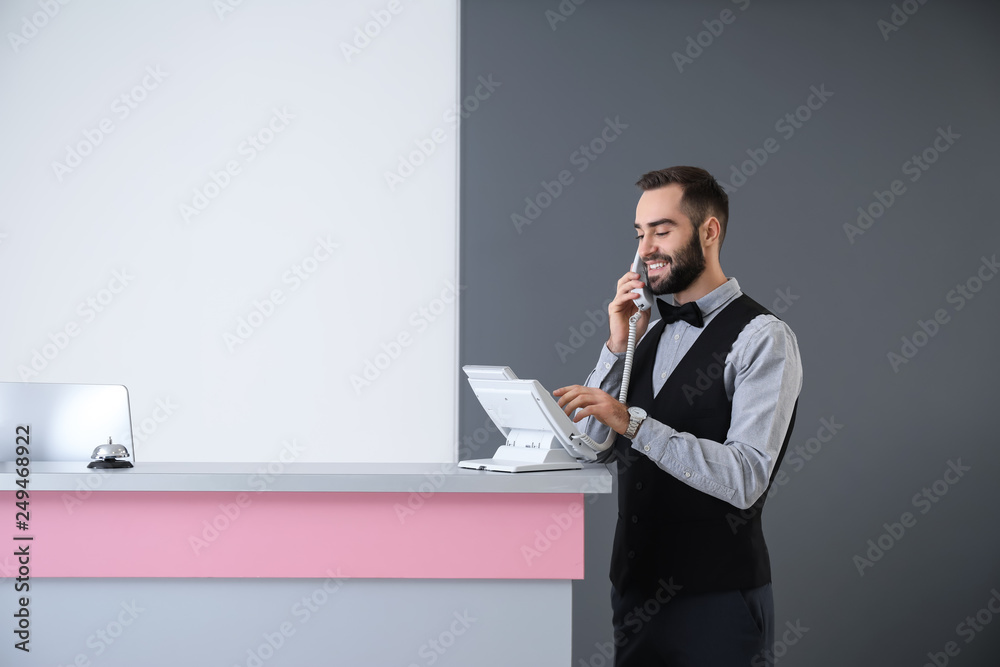 Male receptionist talking by phone in hotel