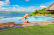 Filipina girl doing yoga poses poolside with ocean background