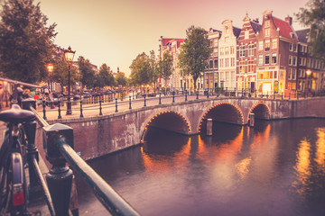 Fototapete - View of the City of Amsterdam with canal and bridge seen at sunset with vintage filter