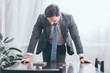 © LIGHTFIELD STUDIOS - sad man in gray suit standing at wooden table and looking at photo in frame at home, grieving disorder concept