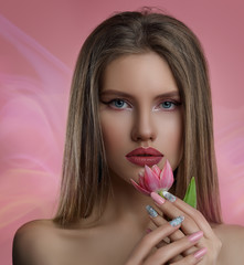 Wall Mural - Beauty portrait of young woman with flower . Model girl with professional make-up and Nail art manicure over pink background.