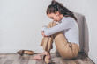 © LIGHTFIELD STUDIOS - sad woman in white blouse and beige pants sitting on floor with head bent near white wall at home, grieving disorder concept