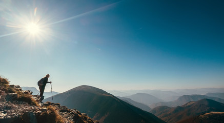 Wall Mural - backpacker hiker on the mountain hill in contrast sun light