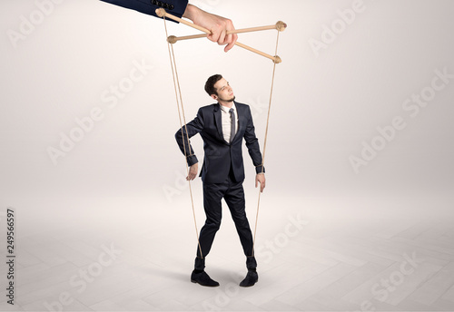 Fotografía Puppet businessman in an empty room leaded by a huge hand