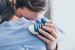 © LIGHTFIELD STUDIOS - cropped view of man hugging woman and holding blue baby shoes in room, grieving disorder concept