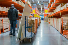 A man in a hardware store. Carts loaded with boards. shop of building materials. Racks with boards, wood and building material. loaded cart in a hardware store