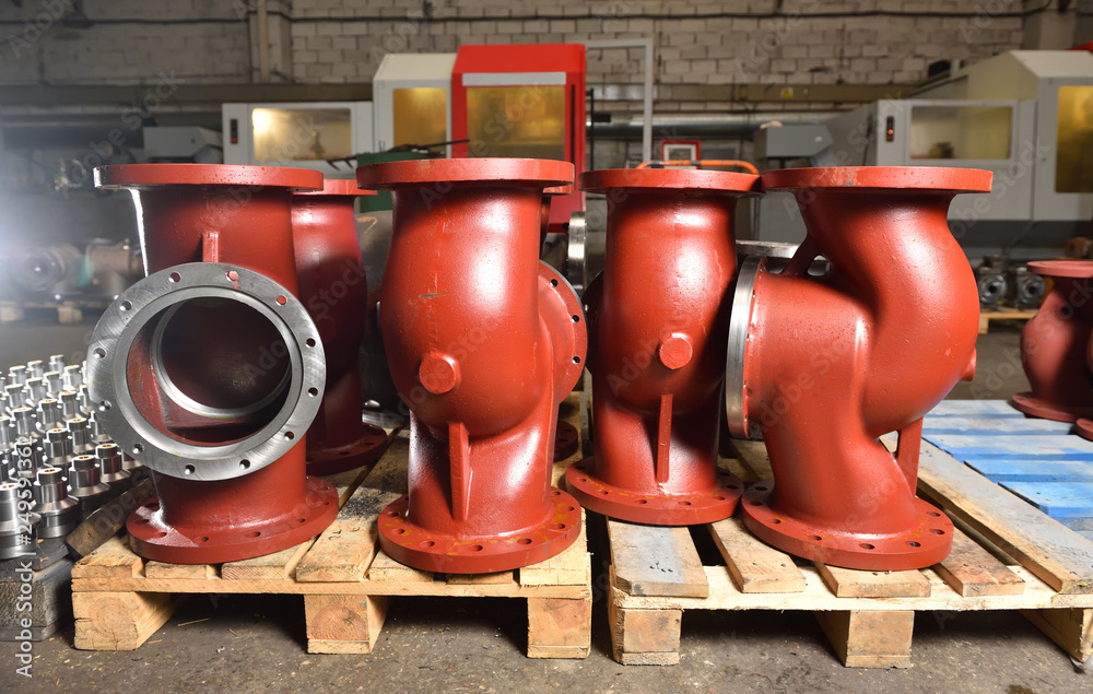 Large metal or cast iron pipes, bases for creating valves, lie on a ...