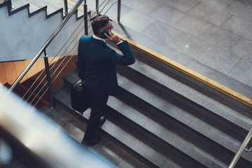 Unrecognizable man walking up on stairs and speaking on telephone