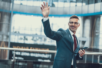 Wall Mural - Friendly man with cellular in hand waving hi