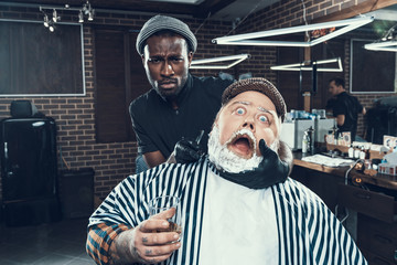 Canvas Print - Barber specialist looking at camera holding client head in hand