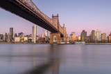 Fototapeta Mosty linowy / wiszący - Queensboro bridge view from east river at sunrise with long exposure