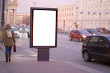 Fototapeta Miasto - vertical billboard for posters, city format, illuminated sign near the road People walking about advertising. outdoor advertising white mockup for advertising