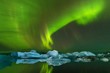 This beautiful northern lights or aurora borealis in Iceland dancing over the above Jokulsarlon glacier lagoon and black beach with icebergs. Beautiful Iceland in winter.Green aurora in christmas time