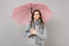 Offended Young Woman In Gray Sweater, Scarf Pouting Lips, Holding Pink Umbrella Isolated On Grey Wall Background. Healthy Fashion Lifestyle People Emotions, Cold Season Concept. Mock Up Copy Space.