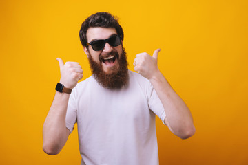 Happy funny bearded man in sunglasses show sight thumbs up and good luck