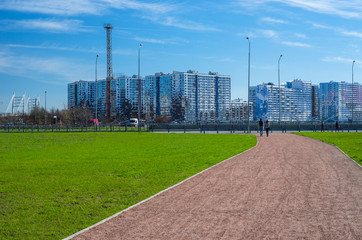 Green lawn and modern apartment buildings. City skyline. Walking zone, comfortable residential quarters. Sunny spring weather. St. Petersburg, Russia, 1 May 2018