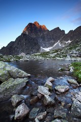 Wall Mural - Spring or summer morning by lake in mountains. Morning beautiful nature scene. High Tatras mountain lake at reflection in water, Carpathians, Slovakia. Beautiful morning background