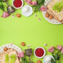 Jewish holiday Passover background with matzo, seder plate and spring flowers.