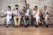 © Mediteraneo - Business people waiting for job interview. They use their phones while waiting