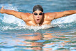 Fit swimmer athlete training butterfly stroke in the swimming pool. Professional male swimmer inside swimming pool.