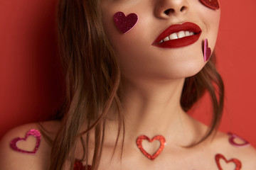 Wall Mural - Cropped photo of brunette girl decorated with heart-shaped stickers indoors