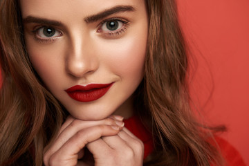  Beautiful portrait of young lady looking at camera on red background