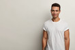© wayhome.studio - Smiling young Caucasian man with pleased expression, dressed in casual clothes, has muscular body, looks directly at camera, isolated over white background with empty space for your advertisement.