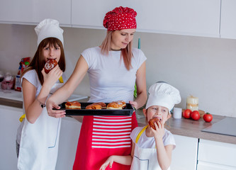 Wall Mural - young girls and mother in chef clothes with baked donuts