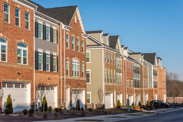 Typical American town house, town home neighborhood with colorful real estate houses at a new construction East Coast Maryland location with blue sky