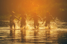 Silhouettes Of Four Children Running On The Water